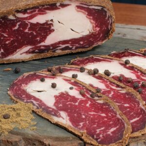 Close-up of sliced cured beef with spices on a rustic wooden board, perfect for gourmet food presentations.